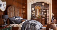 a bed room with a neatly made bed and lots of pillows on the floor in front of a book shelf