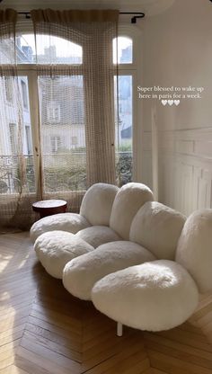 a large white couch sitting on top of a hard wood floor next to a window