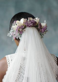 the back of a bride's head wearing a veil and flowers in her hair