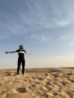 a man standing on top of a sandy beach next to a sky filled with clouds