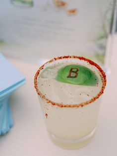 a close up of a drink on a table with a book in the back ground