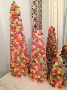 three tall trees made out of gummy balls are sitting on a mantle in front of a mirror