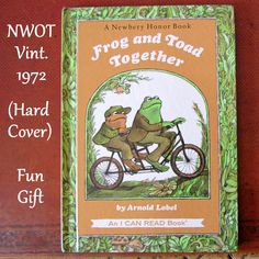 the frog and toad together hard cover book is displayed on a wooden shelf with an orange background