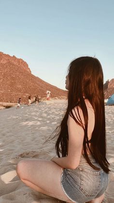 a woman sitting on top of a sandy beach