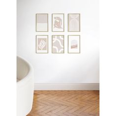 a white chair sitting next to a wall with four pictures on it