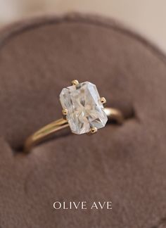 an engagement ring with a cushion cut diamond in it's center, sitting on a velvet box