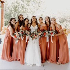 a group of women standing next to each other wearing dresses and holding bouquets in their hands