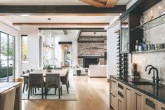 a dining room table and chairs in front of an open fireplace with lots of windows