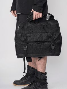 a man holding a large black bag on top of his legs and wearing shorts with no pants