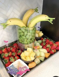 there are many different fruits and vegetables on the trays, including bananas, strawberries, grapes, apples, oranges, and watermelon