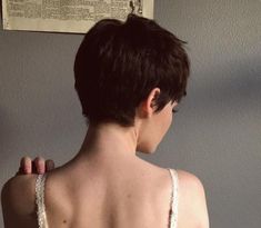 the back of a woman's bra, with her hand on her shoulder and an old newspaper in the background