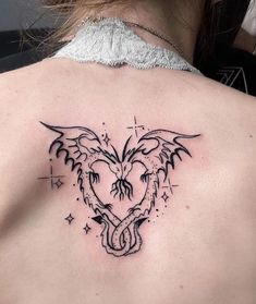 a woman's back with a heart and wings tattoo on her left shoulder, which is surrounded by stars