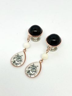 "Plugs and stud earrings capped with rose gold colored setting with a black dome. 13X18mm teardrop with a romantic rose pattern dangles 1.5 inches Perfect to dress up your ears for special occasions Sold in pairs. Purchase a quantity of 1 to receive a pair. IMPORTANT SIZE INFORMATION 10mm tops: Post/stud earrings, 16g, 14g, 12g, 10g, 8g, 6g 12mm tops: 4g, 2g 14mm tops: 0g 00g 000g 18mm tops: 1/2\" 9/16\" 5/8\" 20mm tops: 11/16\" 3/4\" 25mm tops: 7/8\" 1\" PLUG MATERIAL SIZING OPTIONS Post/stud e Adjustable Rose Gold Earrings For Formal Events, Adjustable Rose Gold Earrings For Formal Occasions, Formal Rose Gold Earrings, Rose Gold Metal Drop Clip-on Earrings, Rose Gold Drop Clip-on Earrings, Rose Gold Round Clip-on Earrings For Gift, Rose Gold Round Clip-on Earrings As Gift, Elegant Adjustable Rose Design Earrings, Wedding Gauges