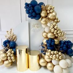 a table topped with gold and blue balloons in the shape of a christmas tree surrounded by other decorations