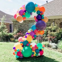 a bunch of balloons that are on the ground in front of some grass and a house