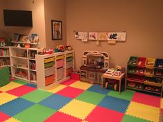 a child's playroom with toys and bookshelves on the walls, carpeted in multicolored tiles