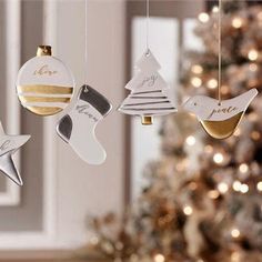 three christmas ornaments hanging from strings in front of a christmas tree