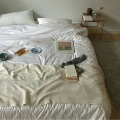 an unmade bed with books and other items on it