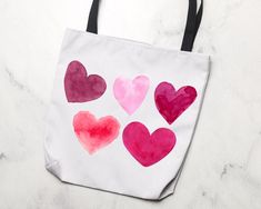 a white bag with pink and red hearts painted on the side, sitting on a marble surface