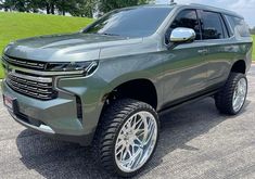 a grey chevrolet suburban is parked in a parking lot with its wheels on the ground