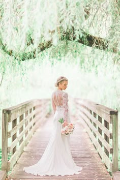 a woman in a wedding dress standing on a bridge