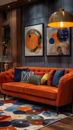 a living room with orange couches and art on the wall behind it, along with two lamps