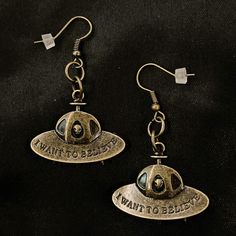 "These are fun, kitschy, and adorable! It's a pair of bronze UFO earrings with an alien head peaking out of the window, and they say I Want To Believe. They are hung on bronze metal ear wires. 2\" long, each dangle is just under 1 1/2\" long and 1 1/4\" wide. Make sure to check out my shop for all sorts of hair accessories, jewelry, magnets, trinket boxes, coasters, and more! UFO Earrings, I Want To Believe, UFO Jewelry, Alien Earrings, Alien Jewelry, Spaceship Jewelry, Spaceship Earrings, Flyin Spaceship Earrings, Ufo Earrings, Alien Jewelry, Ufo Jewelry, Alien Earrings, Puppy Paw Prints, Alien Head, I Want To Believe, Flying Saucer