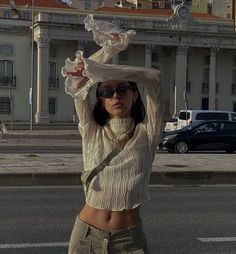 a woman standing in the middle of a street with her hands on her head and arms behind her head