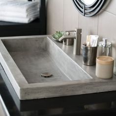 a bathroom sink sitting under a mirror next to a towel dispenser and toiletries