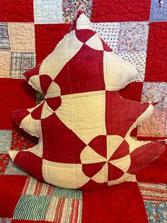 a red and white teddy bear sitting on top of a quilt