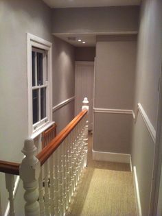 an empty hallway with white railings and wood baluster on the right hand side