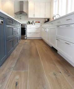 a kitchen with white cabinets and wood floors is shown in this image from the front view