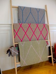 a ladder is holding several pieces of fabric in different colors and patterns on the wall