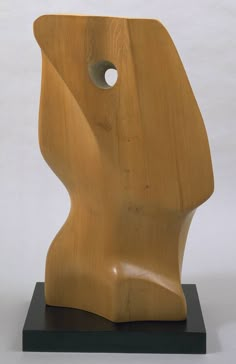 a wooden sculpture sitting on top of a black base with a hole in the middle