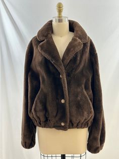 This 80s brown faux fur jacket is one of a kind. In a bomber style, it buttons up the front, has an elastic waist, pockets.  a great collar and is super cozy. Pair this with flared jeans or oversized joggers. -Vintage 80s  -Bomber style, faux fur -Professional fur cleaner recommended  Measurements:  I am a size 38d, 34 waist, 40 hips and this fit me well, can be an oversized fit also *Sleeve 22 1/2 inches *Bust 21  inches *Length 22 inches from shoulder *Bottom 17 inches *Please note this item i Brown Fur Coat With Buttons For Fall, Winter Brown Fur Coat With Pockets, Brown Fur Coat With Button Closure For Fall, Brown Winter Fur Coat With Button Closure, Brown Fur Coat With Faux Fur Lining, Cozy Brown Long Sleeve Fur Coat, Cozy Brown Outerwear With Faux Fur Trim, Brown Cozy Fur Coat With Faux Fur Lining, Brown Faux Fur Lined Outerwear