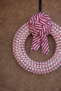 a red and white wreath with a bow hanging on the front door ornament