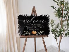 a welcome sign sitting on top of a easel next to a potted plant