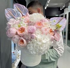 a man holding a large bouquet of flowers in his hands with wings on it's back