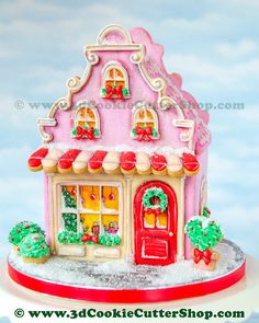 a pink gingerbread house with christmas decorations on it's roof and windows is shown