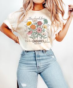 a woman in ripped jeans and a t - shirt with flowers on it is posing for the camera