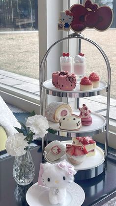 a tiered tray with hello kitty cupcakes and other desserts on it