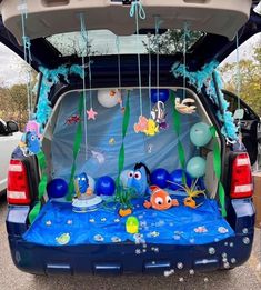 the back end of a blue car with balloons and decorations in it's trunk