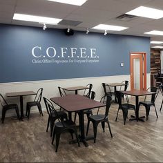 the inside of a coffee shop with tables and chairs in front of a wall that says coffe