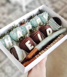 a person holding a box filled with chocolates and strawberries that say happy eid