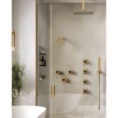 a bathroom with gold fixtures and a white bathtub next to a shower head, toilet paper dispenser on the wall