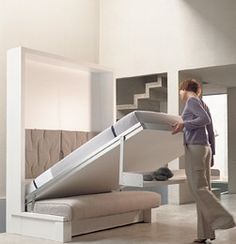 a woman walking past a bed with a slide on the bottom and footrests