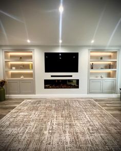 a living room with a large television mounted on the wall and built - in shelving