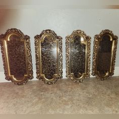 four ornate gold frames lined up against a wall