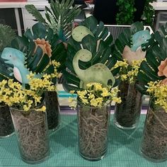 four vases filled with plants and flowers on a table