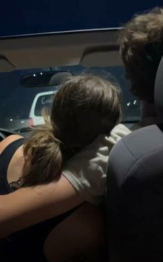 two people hugging each other in the back seat of a car